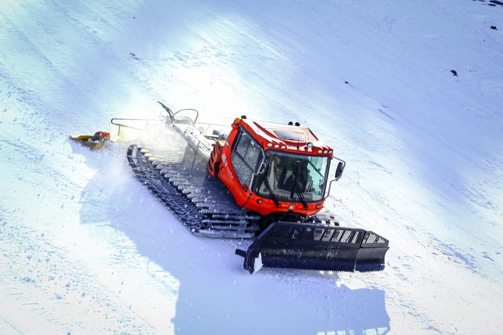 orange and black snow blower on snow covered ground during daytime