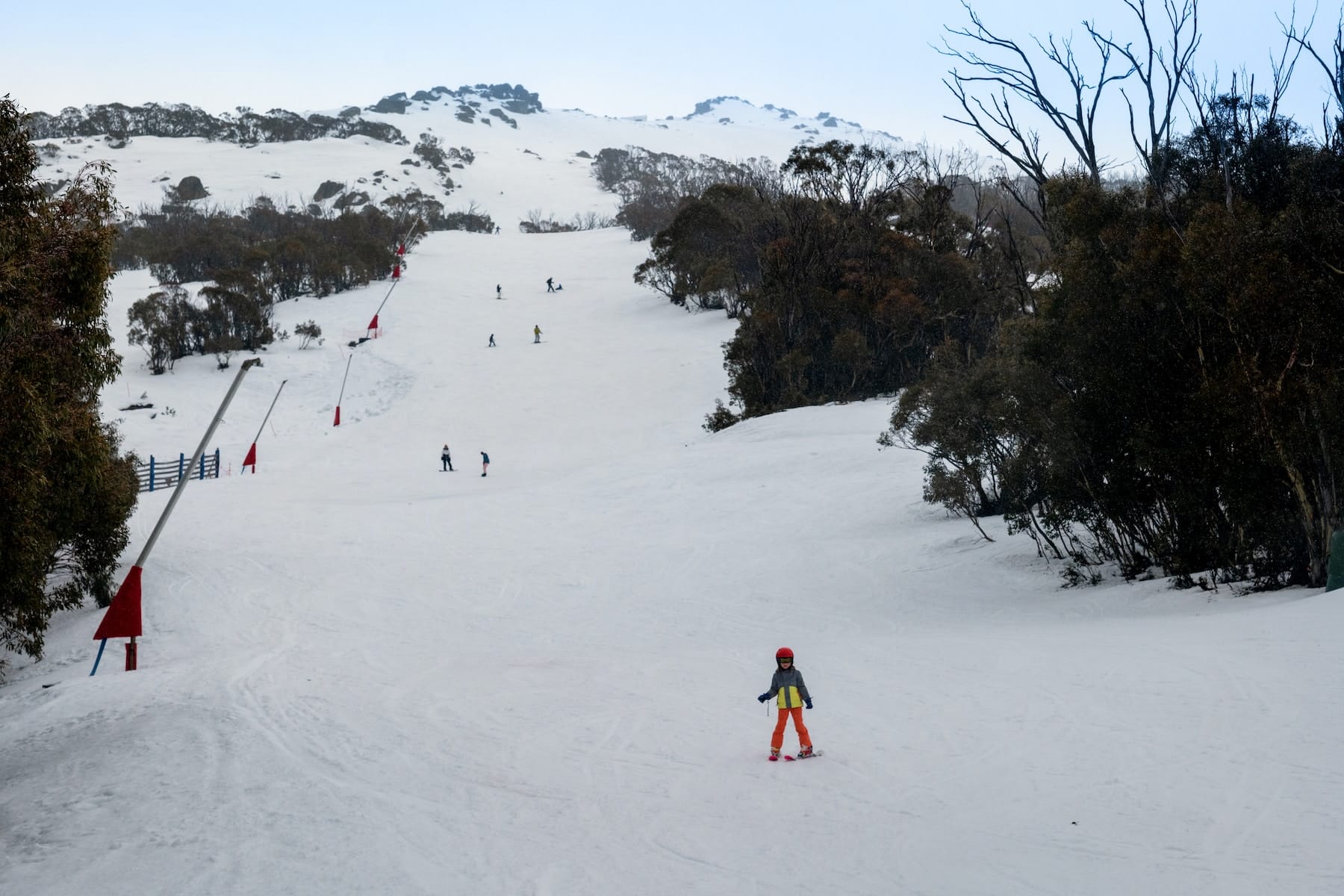 person in red jacket walking on snow covered field during daytime